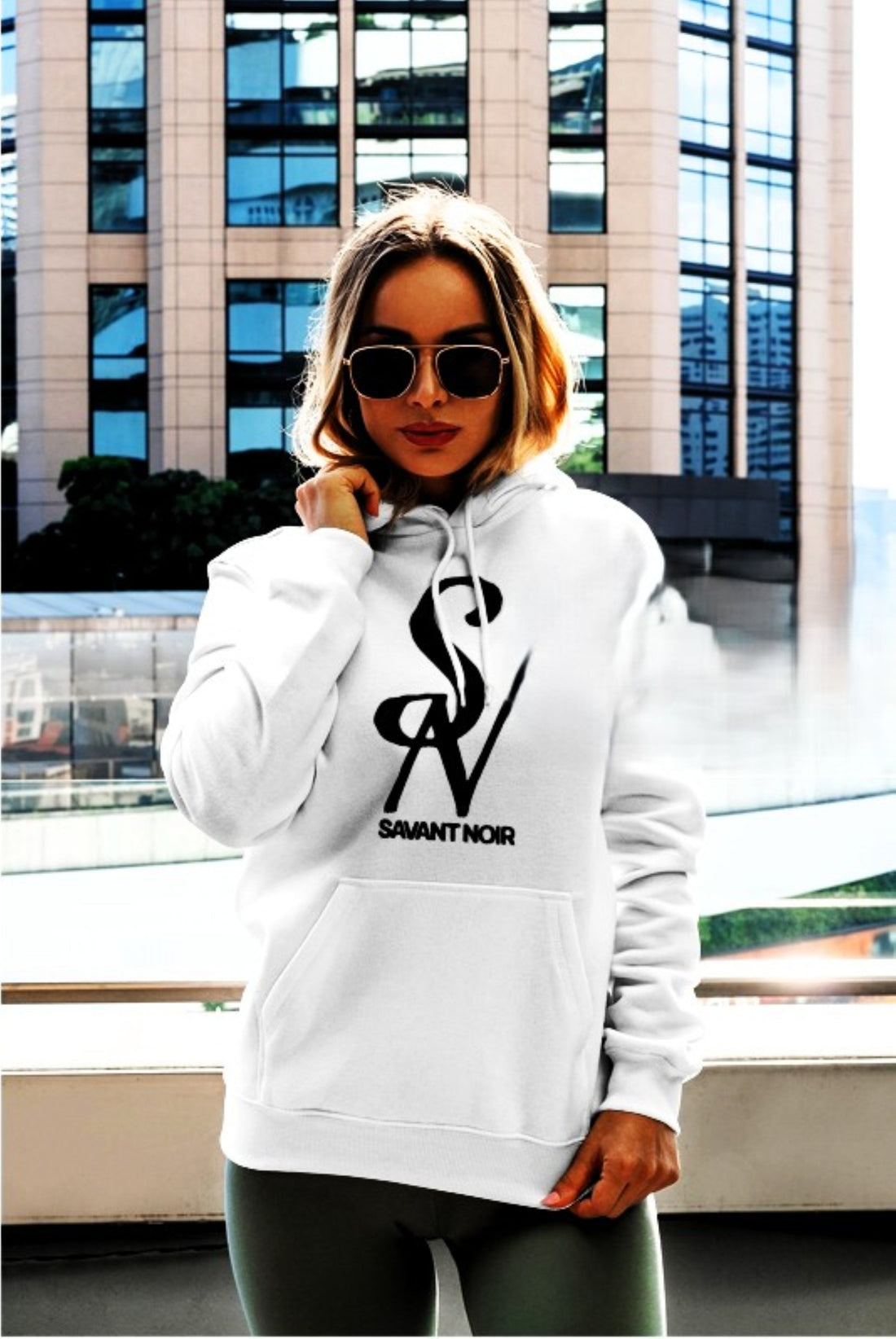 Woman wearing a white oversized hoodie with sunglasses showcasing luxury streetwear outfit ideas in urban setting