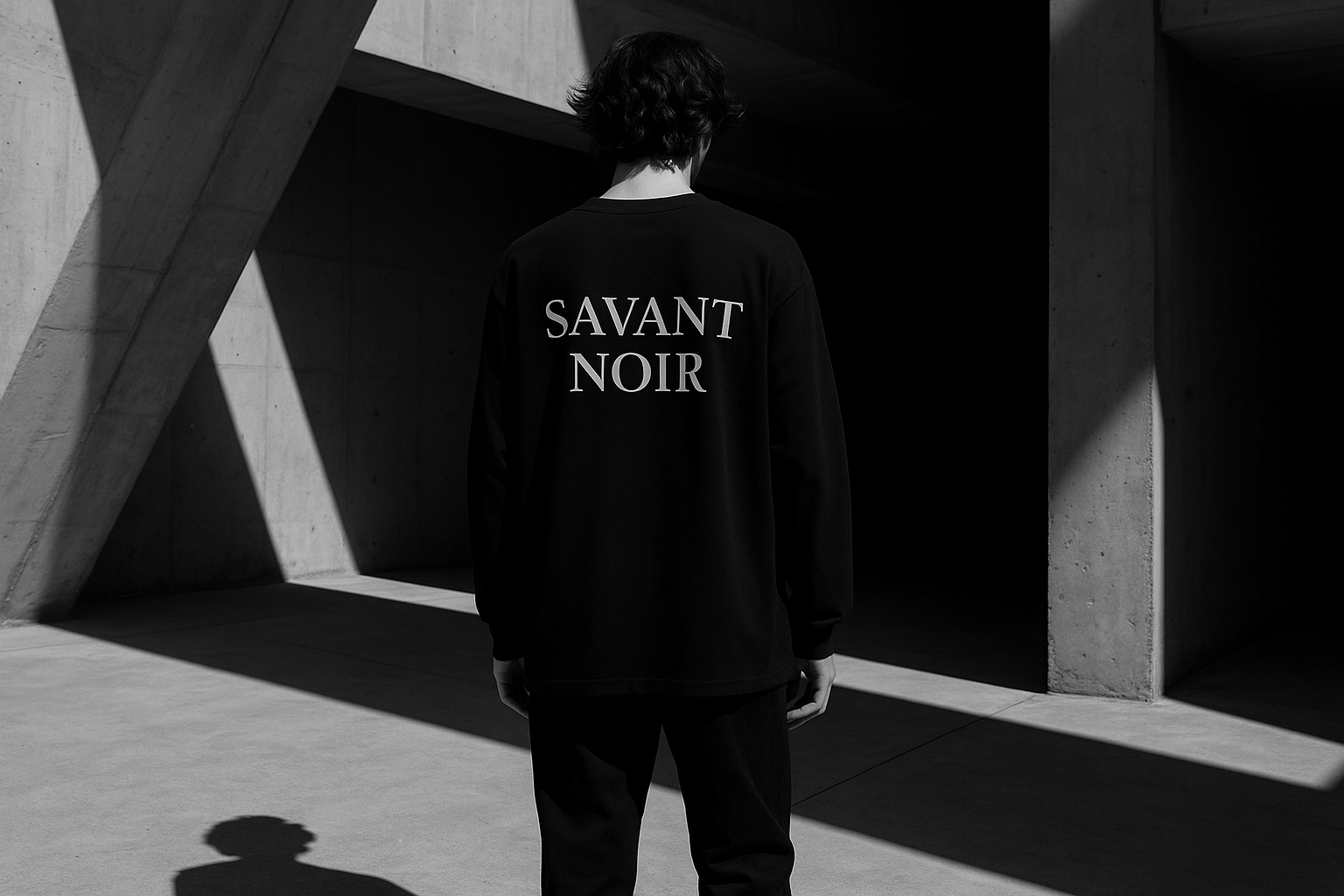 Man wearing black luxury streetwear pants and matching hoodie with Savant Noir logo in an urban street setting