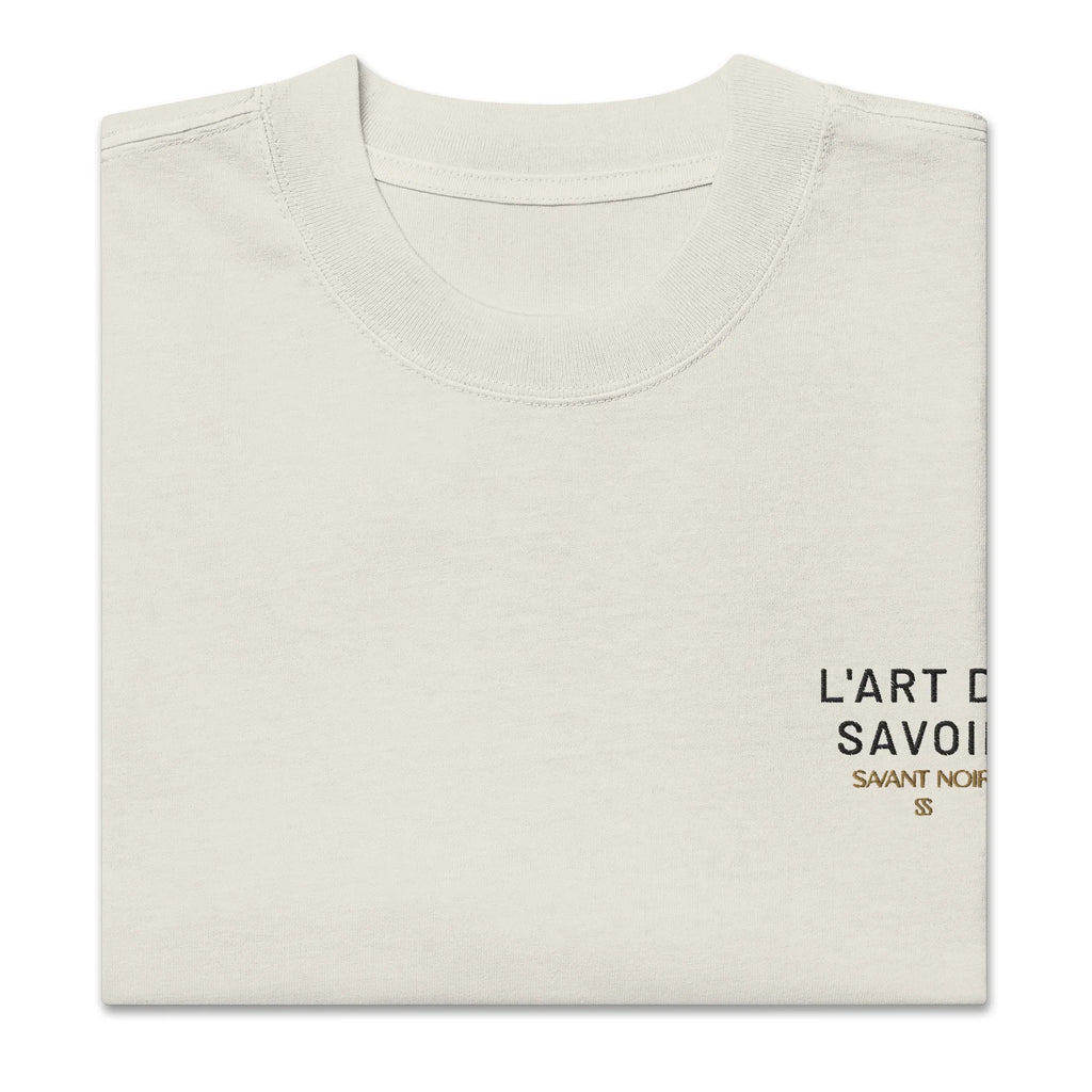 SAVANT NOIR luxury oversized streetwear tee in beige with minimalist black logo print folded neatly