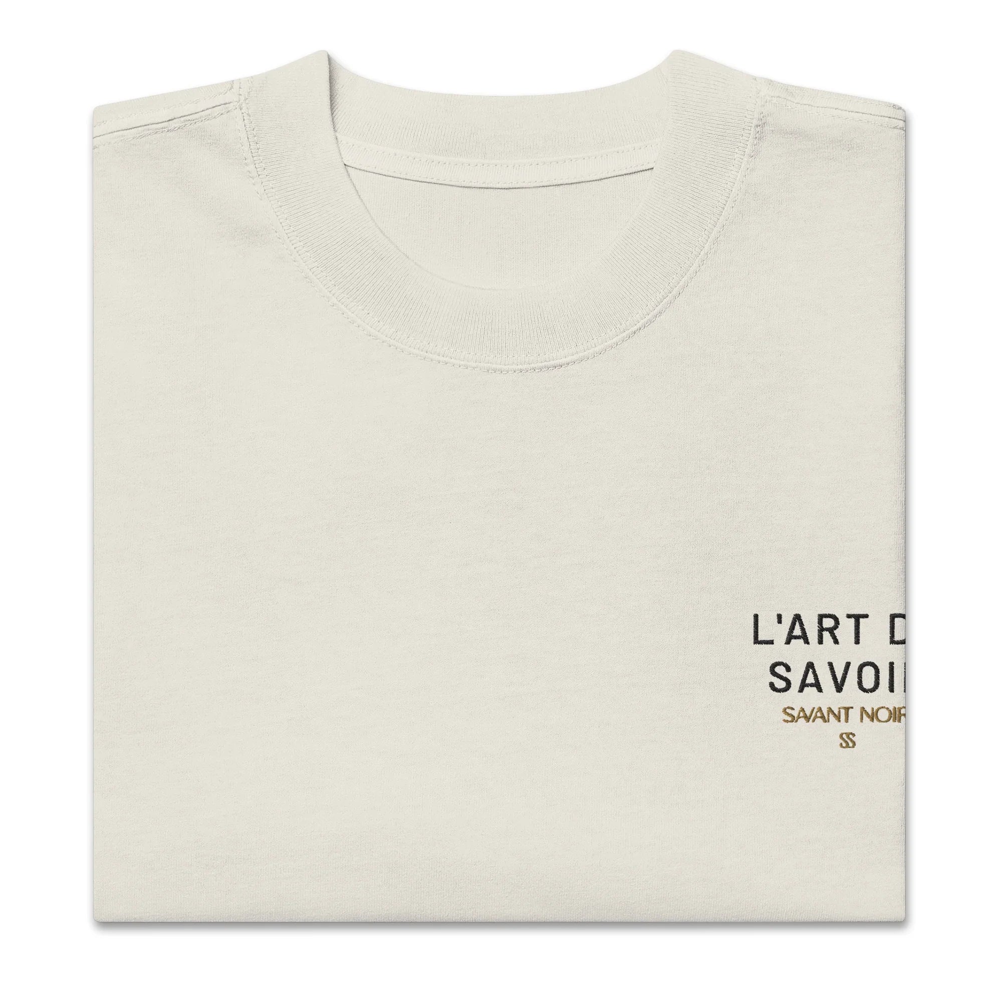 SAVANT NOIR luxury oversized streetwear tee in beige with minimalist black logo print folded neatly