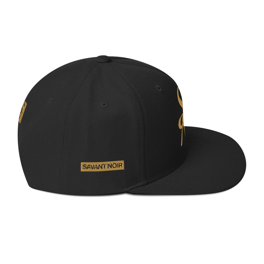 Black luxury snapback hat by SAVANT NOIR with gold embroidered logo and flat brim