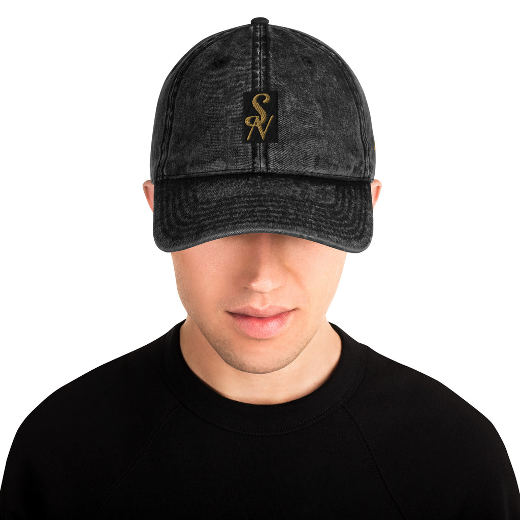 SAVANT NOIR vintage cotton twill cap in black worn by a male model with gold logo patch